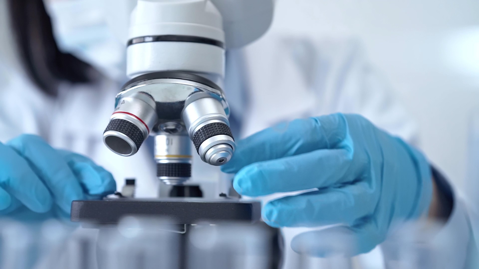 Scientist using microscope in laboratory. Close-up of a researcher's hands adjusting a modern microscope in a lab setting. Science concept